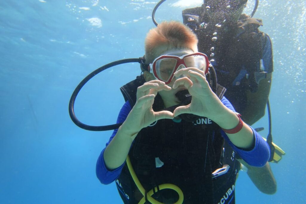 Nurkowanie z butlą Hurghada – zbliżenie nurka z gestem serca pod wodą